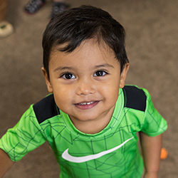 Child smiling while standing in classroom environment