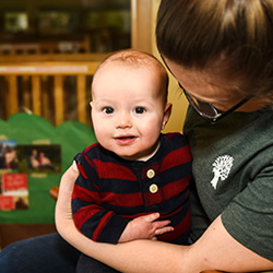 Baby boy sitting on teachers lap in rocking chair